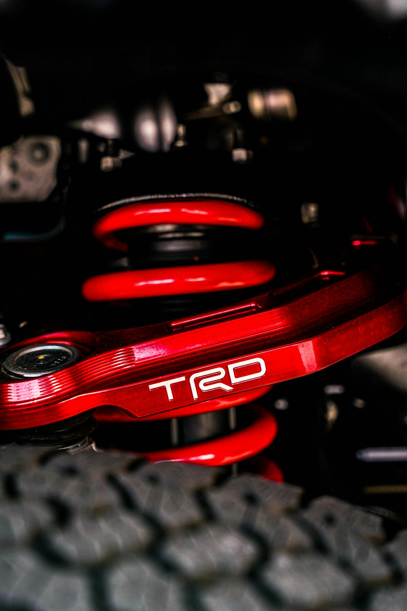 Close-up of a vibrant red TRD suspension system highlighting car engineering details.